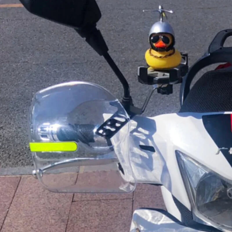 Motorcycle with clear hand guard and handlebar-mounted rubber duck in helmet and sunglasses