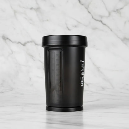 A black shaker bottle with a matching lid, featuring a clear measurement window and white vertical 'HELEMEI' branding, set against a white marble background.