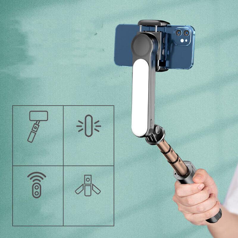 Hand holding extendable selfie stick tripod with smartphone and LED light, indoor setting