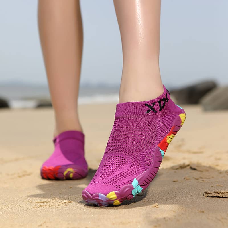 Purple beach shoes with colorful sole design on a sandy background