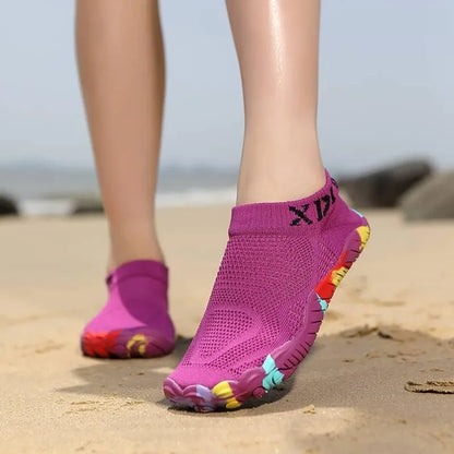 Pink water shoes with colorful soles on a sandy beach