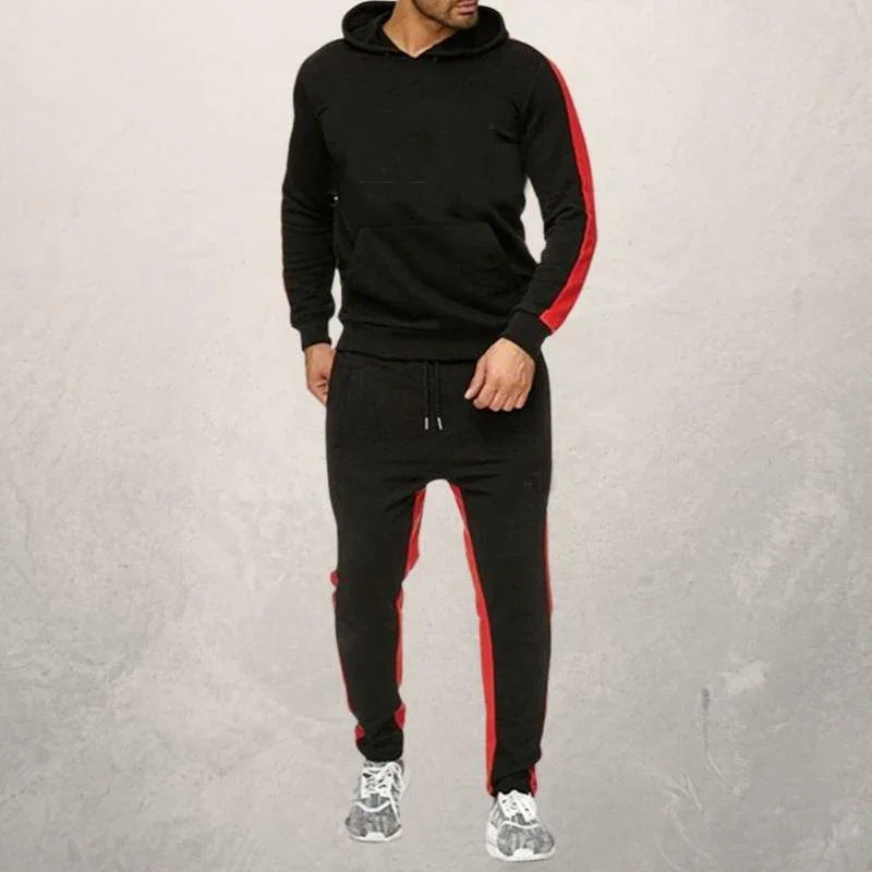 Man wearing black hoodie and joggers with red stripes, paired with gray athletic shoes, fitness apparel