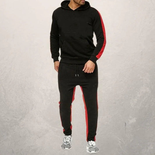 Man wearing black hoodie and joggers with red stripes, paired with gray athletic shoes, fitness apparel