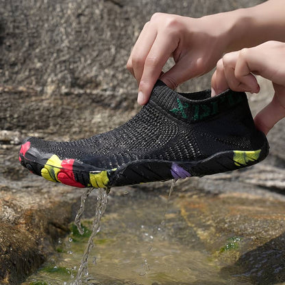 Person wearing a black water shoe with colorful sole over a stream
