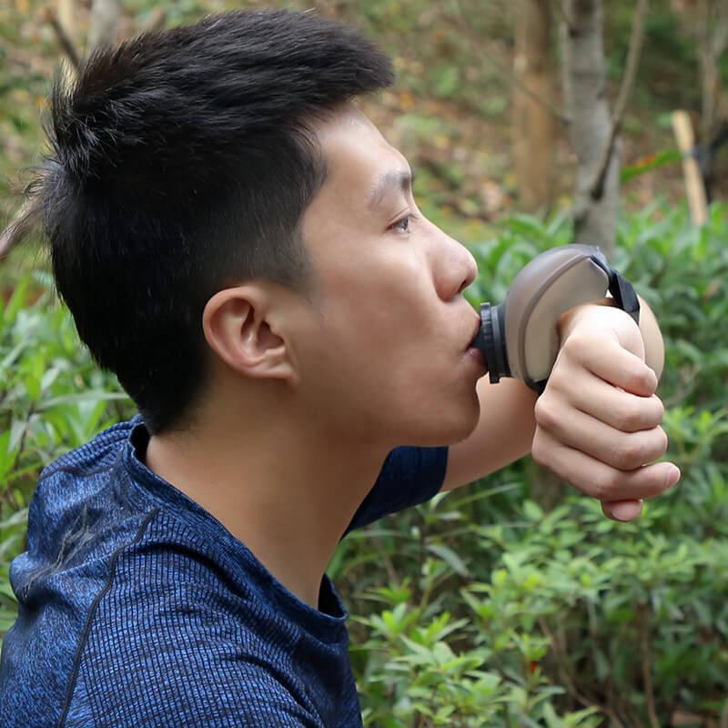 Man outdoors drinking from wearable water bottle for fitness and hiking
