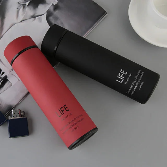 Two sleek LIFE vacuum cups in red and black on a gray surface, ideal for fitness hydration