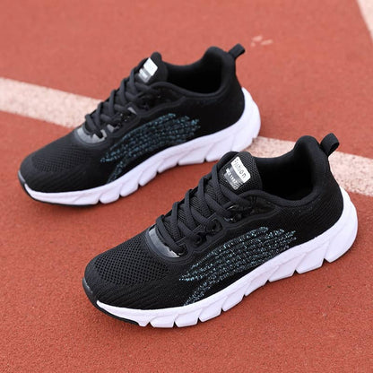 Black athletic running shoes with white soles on a red track surface