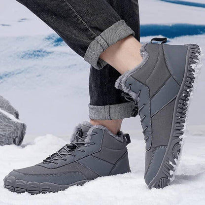 Gray winter hiking boots with fur lining and rugged soles on snowy ground
