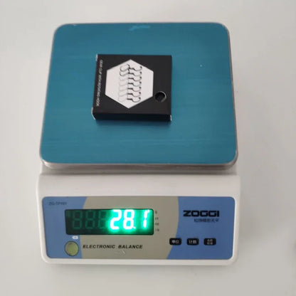 Small black fitness accessory on digital scale showing 28.1 grams weight
