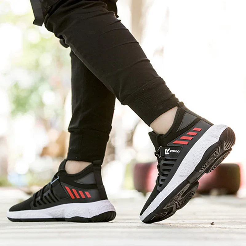 Close-up of black and white running shoes with red accents worn by a person in black pants, outdoor fitness setting