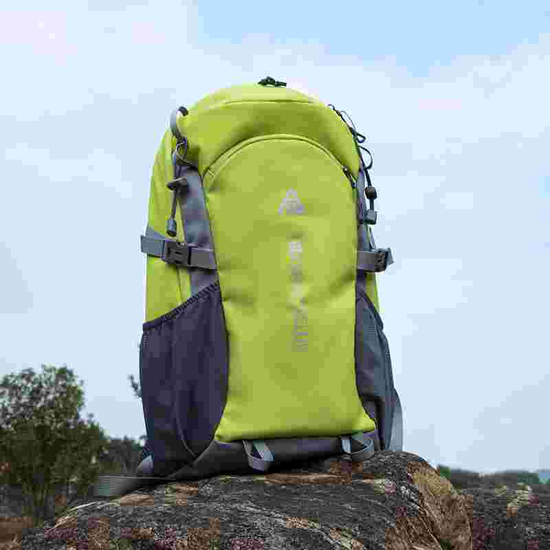 Green and gray backpack on a rock with a blurred natural background