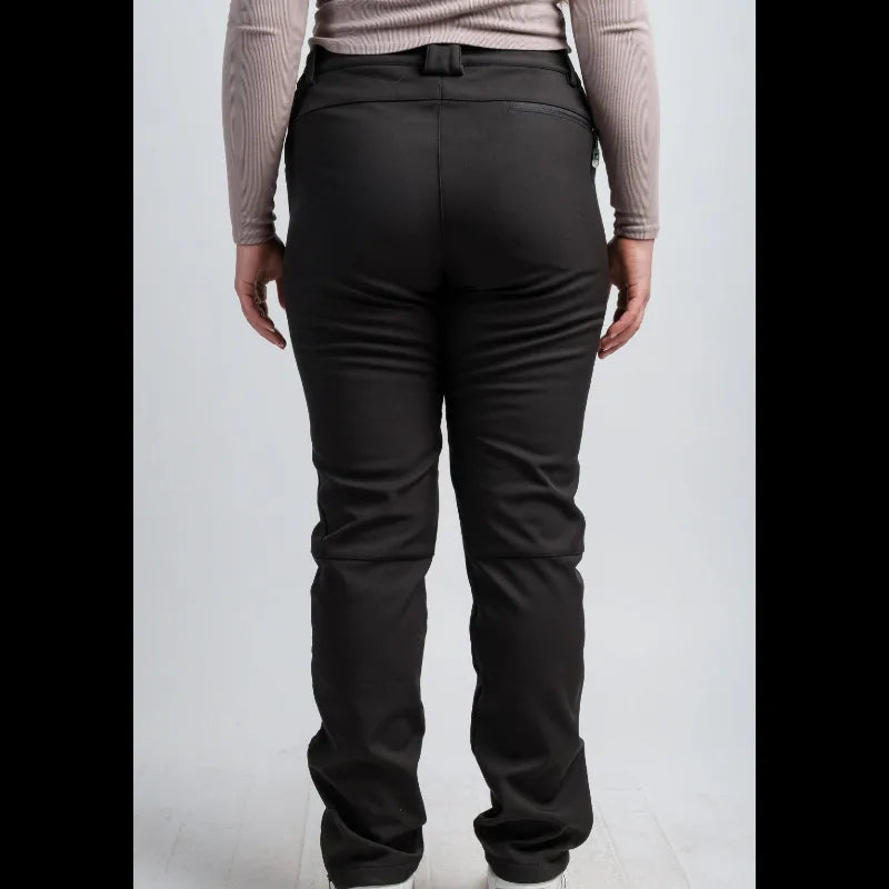 Rear view of a person wearing black pants with a matching black belt, paired with a light beige long-sleeve top and white sneakers, against a light gray studio background.