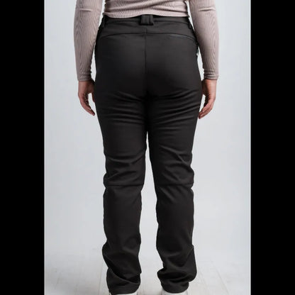 Rear view of a person wearing black pants with a matching black belt, paired with a light beige long-sleeve top and white sneakers, against a light gray studio background.