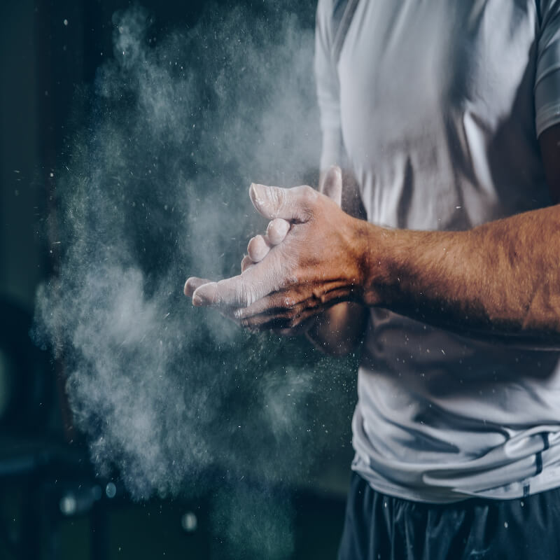Person applying white powder to their hands with a dark background