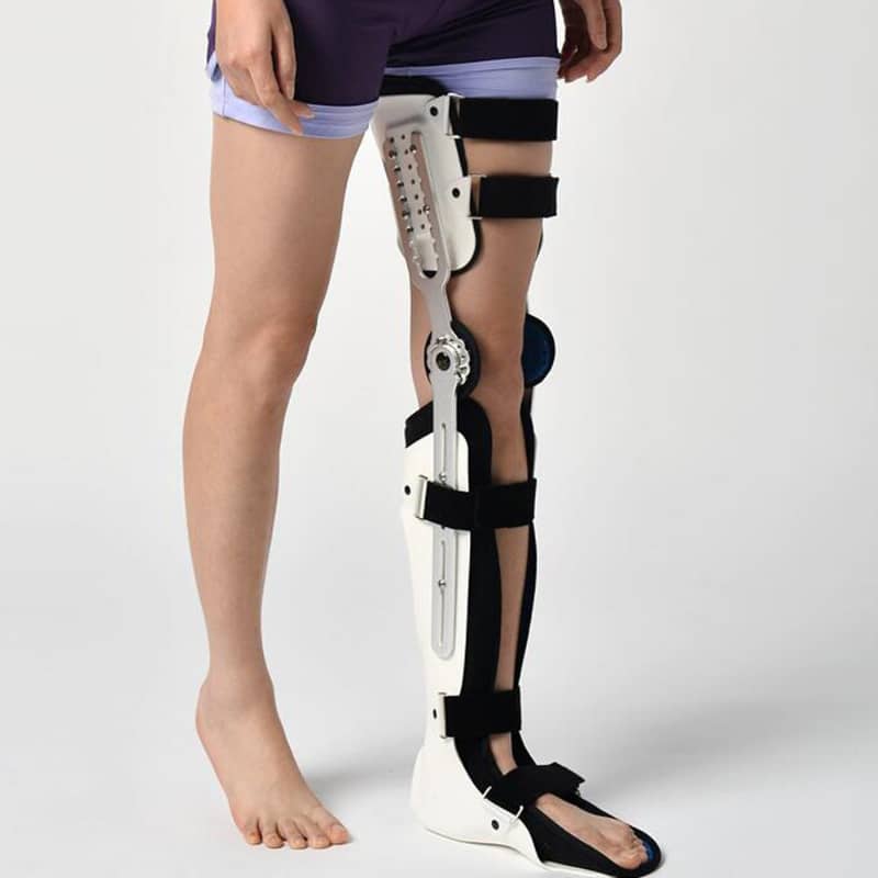 Person wearing adjustable full-leg orthopedic knee brace with support straps