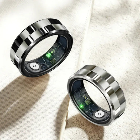 Two metal smart fitness rings with circuit boards and glowing green lights on fabric background