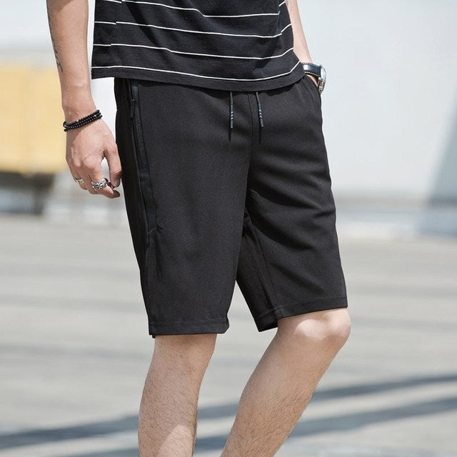 Person wearing black shorts and a striped shirt on a blurred outdoor background