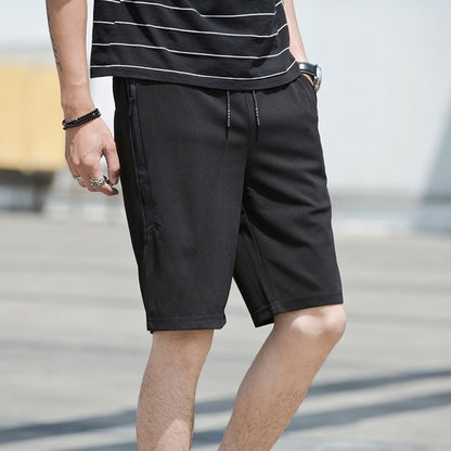 Person wearing black shorts and a striped shirt on a blurred outdoor background