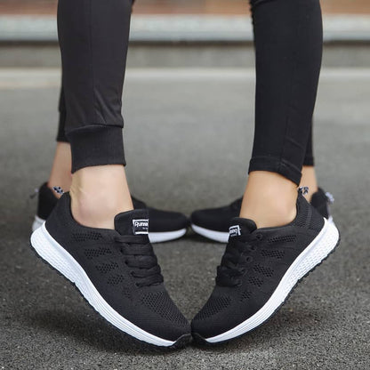 Black running shoes with white soles worn by a person on a blurred background