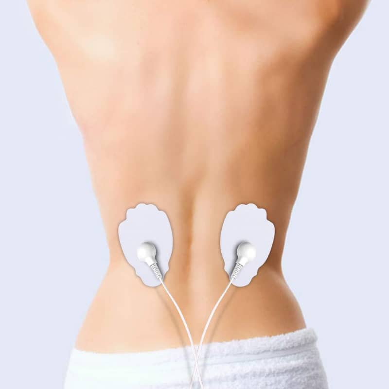 Electrode pads on a person's lower back with a plain background