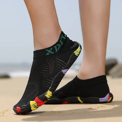 Black socks with colorful toe pads worn on a beach.