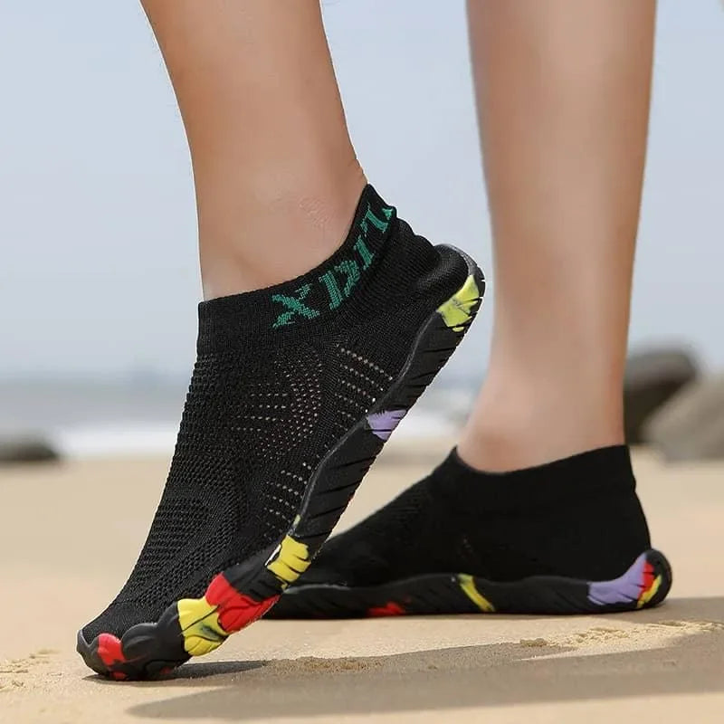 Black socks with colorful toe pads worn on a blurred beach background