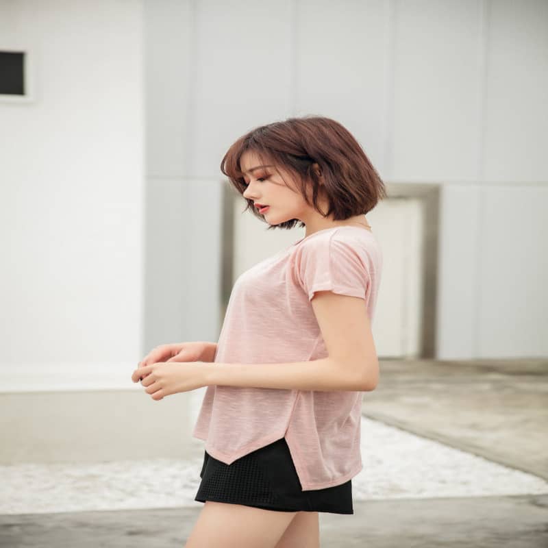 Woman wearing a pink top and black shorts in an indoor setting