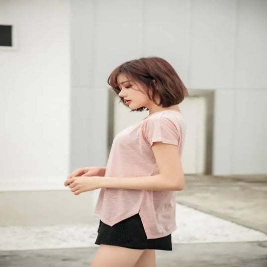 Woman wearing a pink top and black shorts in an indoor setting