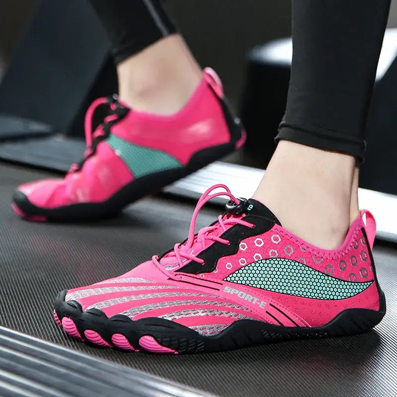Pink minimalist athletic shoes with grip soles worn on treadmill, fitness workout footwear