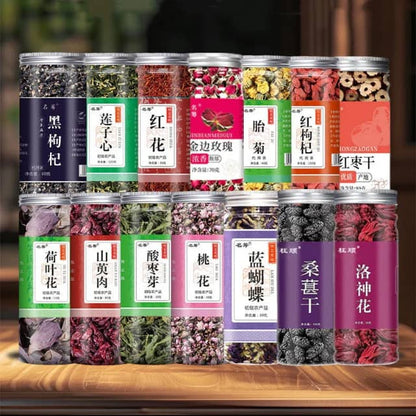 Assorted jars of dried herbs and flowers for tea or wellness, displayed on a wooden table.