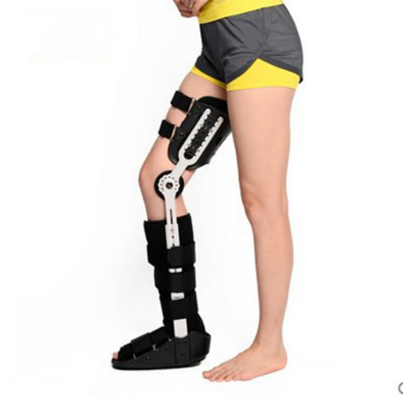 Person wearing adjustable knee and leg brace orthopedic support on left leg
