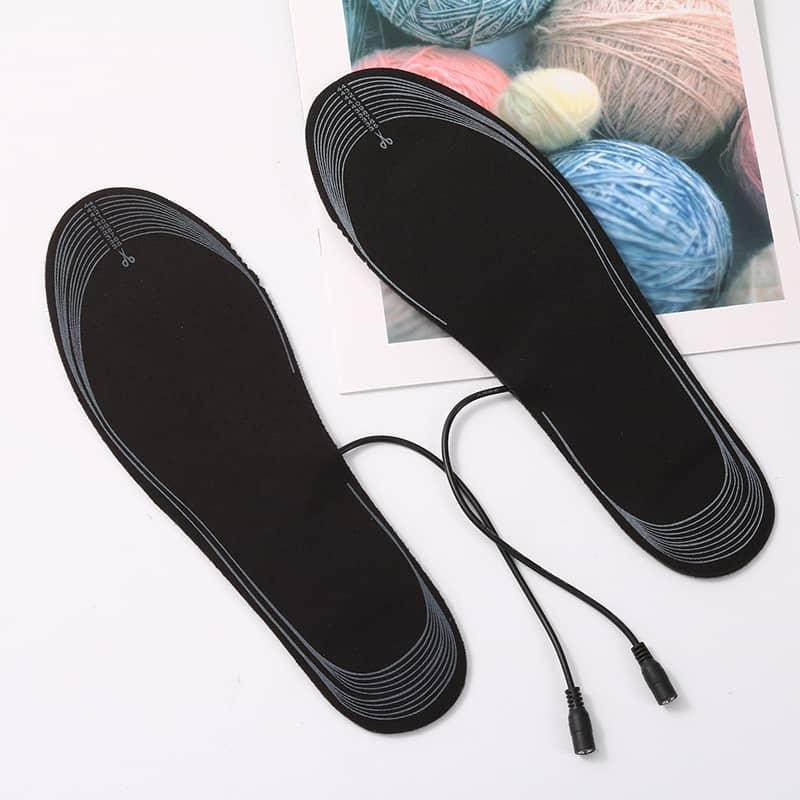 Black heated insoles with attached power cables on white surface, ideal for fitness and outdoor activities
