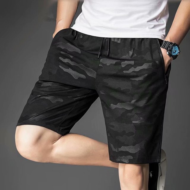 Person wearing black camouflage shorts on a gray background