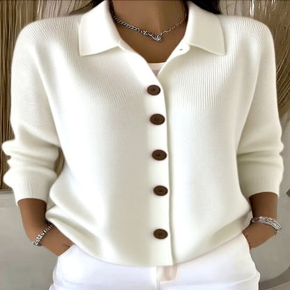 White button-up shirt with brown buttons worn by a person, against a neutral background