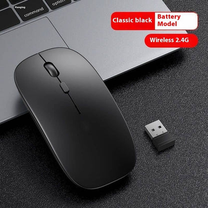 Black wireless mouse with USB receiver on a dark surface, next to a laptop.
