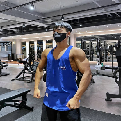 Person wearing a blue tank top with 'FZCA' logo in a gym setting