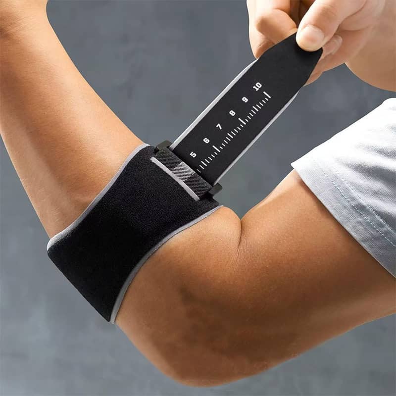 Person adjusting a black wrist support brace with measurement markings on a gray background