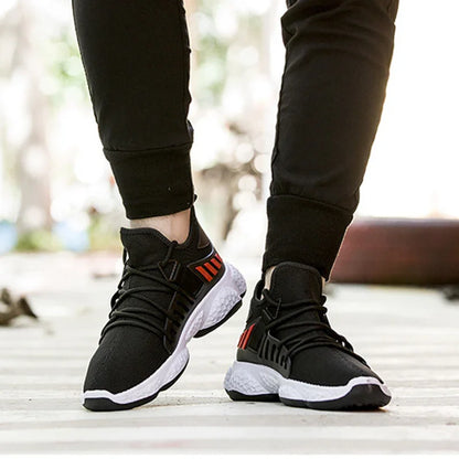 Close-up of person wearing black and white athletic sneakers with red accents and black joggers on outdoor path