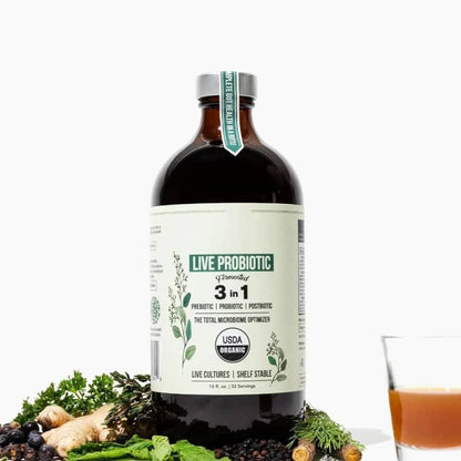 Organic live probiotic supplement bottle with fresh herbs and a glass of probiotic drink