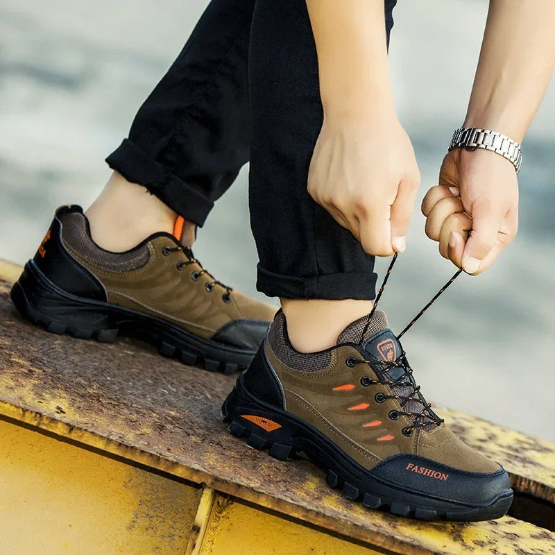Person tying brown outdoor hiking shoes with rugged soles, standing on a rusty surface