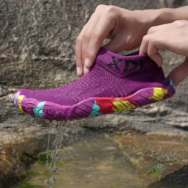 Purple water shoe with colorful sole being held over a stream