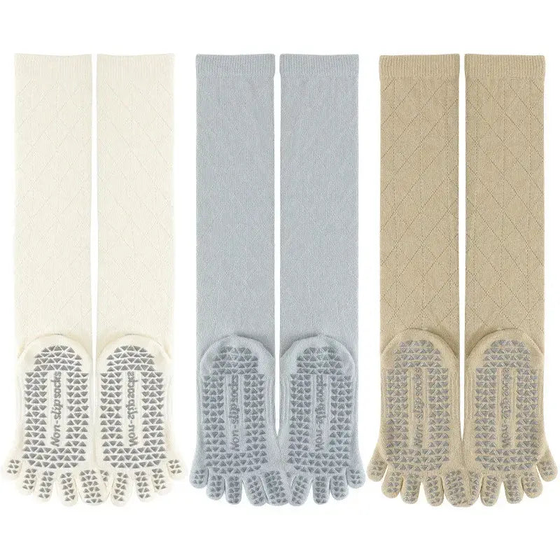 Three pairs of knee-high toe socks with grip soles, in cream, gray, and beige, for yoga or fitness.