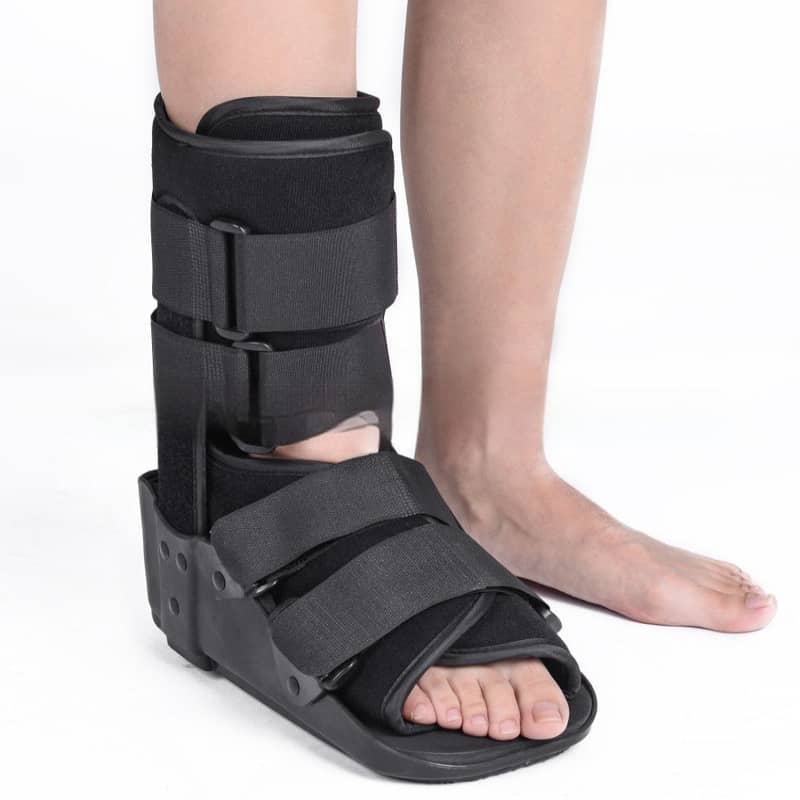 Black foot cast brace on a person's leg against a white background
