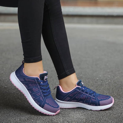 Navy running shoes with pink accents worn by a person on a road.