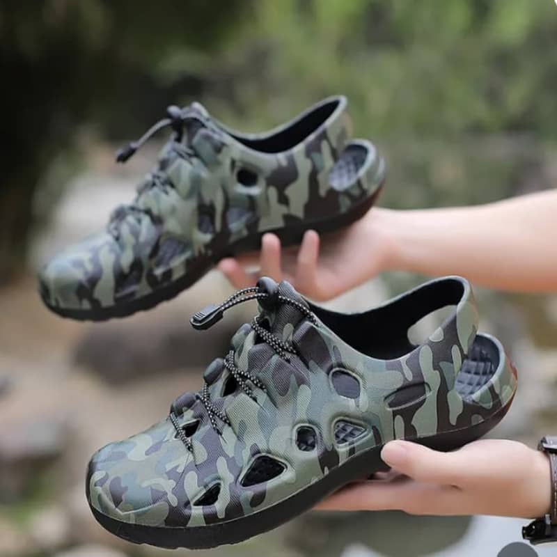 Camouflage-patterned shoes held by a person with a natural background