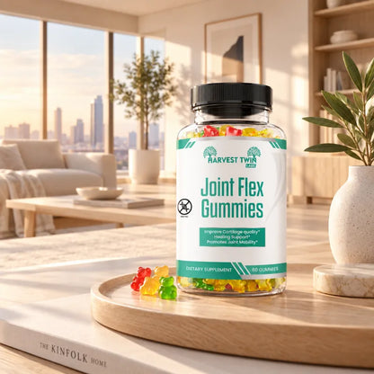 A bottle of Harvest Twin Joint Flex gummy supplements sits on a wooden tray in a modern, sunlit living room. The clear bottle shows multicolored gummies inside, with a few scattered on the tray.